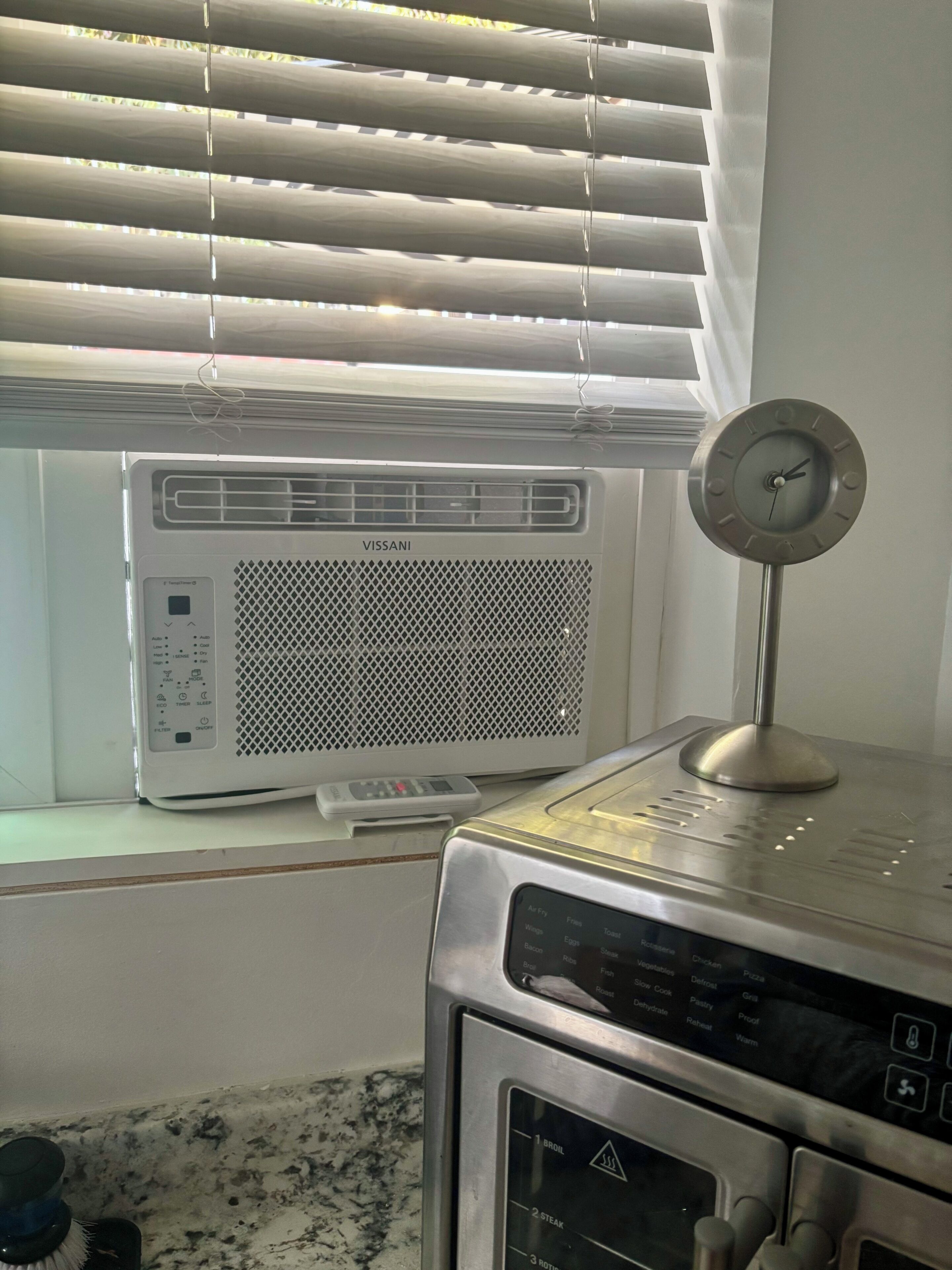 Une cuisine équipée d’un climatiseur intégré, d’une horloge et d’un four à micro-ondes.