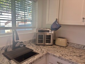 A kitchen with a built-in oven, a toaster, and a sink.