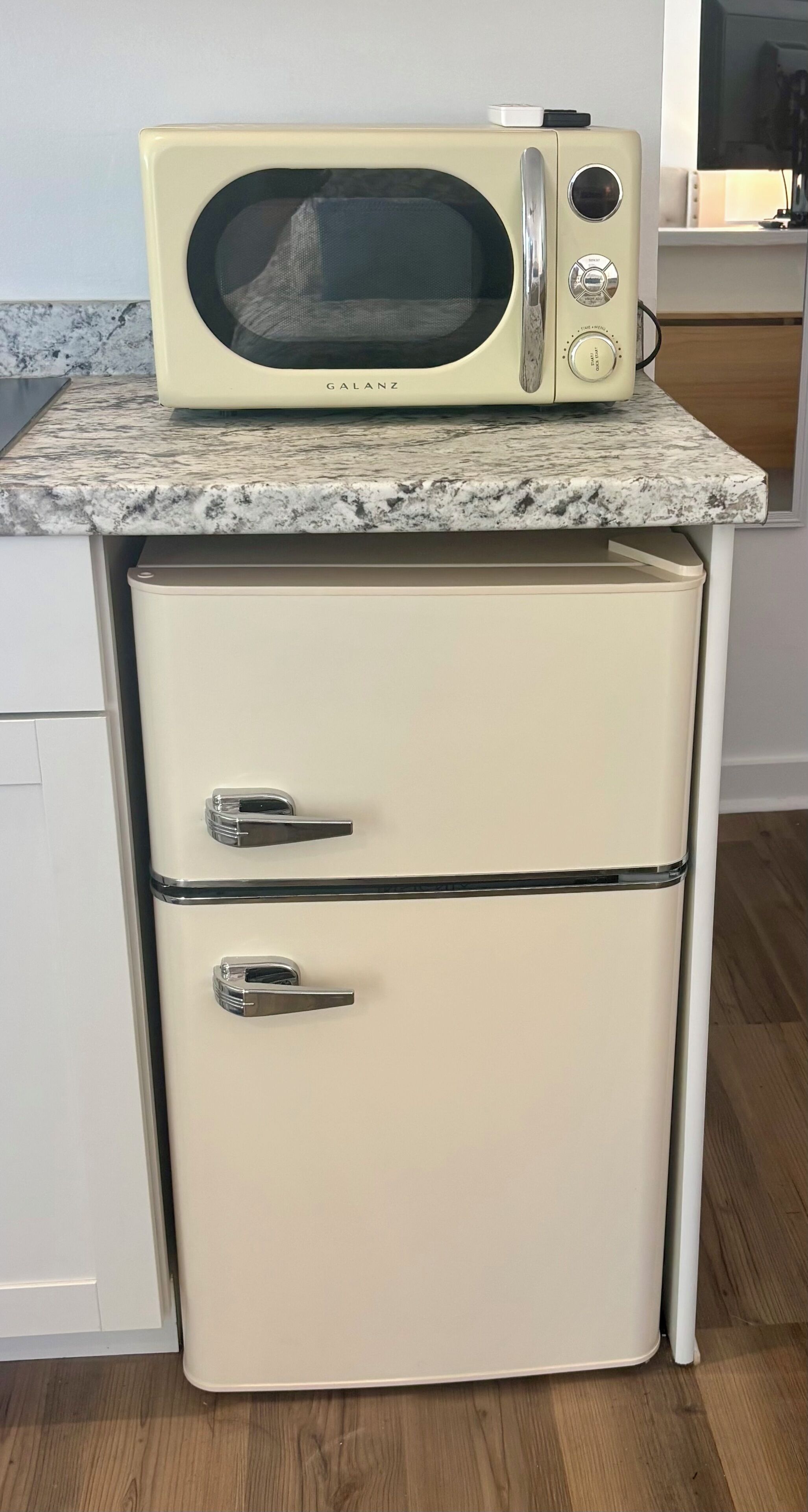 Une petite cuisine d’époque, avec un micro-ondes posé sur un meuble blanc, comprenant deux tiroirs et une porte dotée d’une poignée.