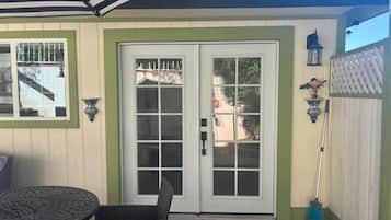 A patio with a table and chairs, a white door with glass panels, and a blue broom leaning against the wall.