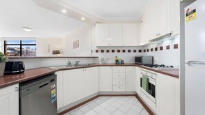 Una cucina moderna con mobili bianchi, lavastoviglie, fornello e microonde.