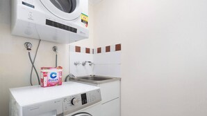 Una lavanderia funzionale con lavatrice a carica frontale, asciugatrice e un piccolo lavandino.