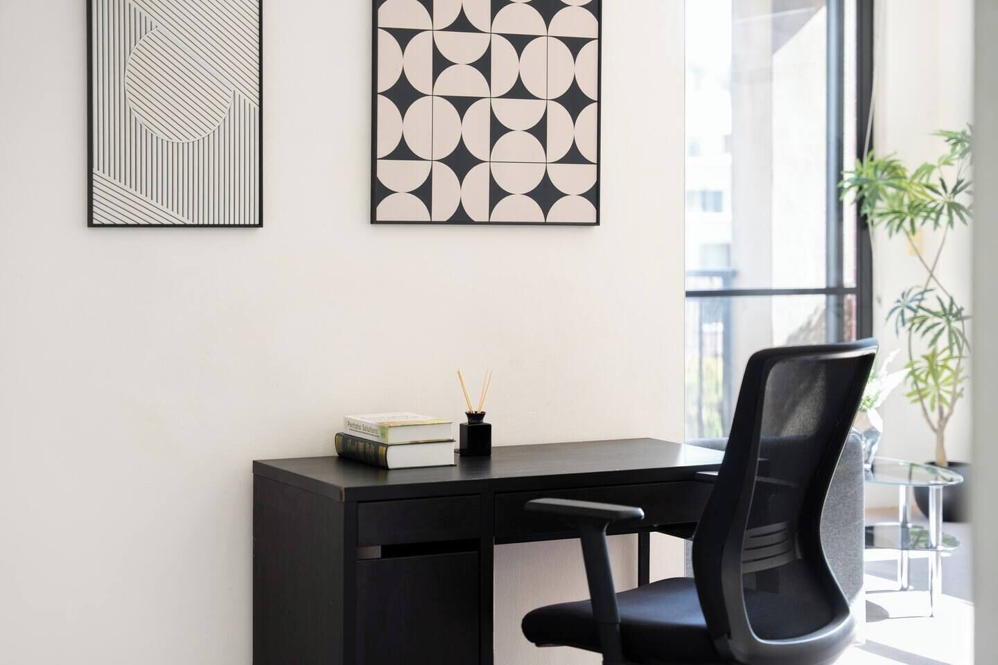 A modern office space with a desk, chair, and two framed artworks on the wall.