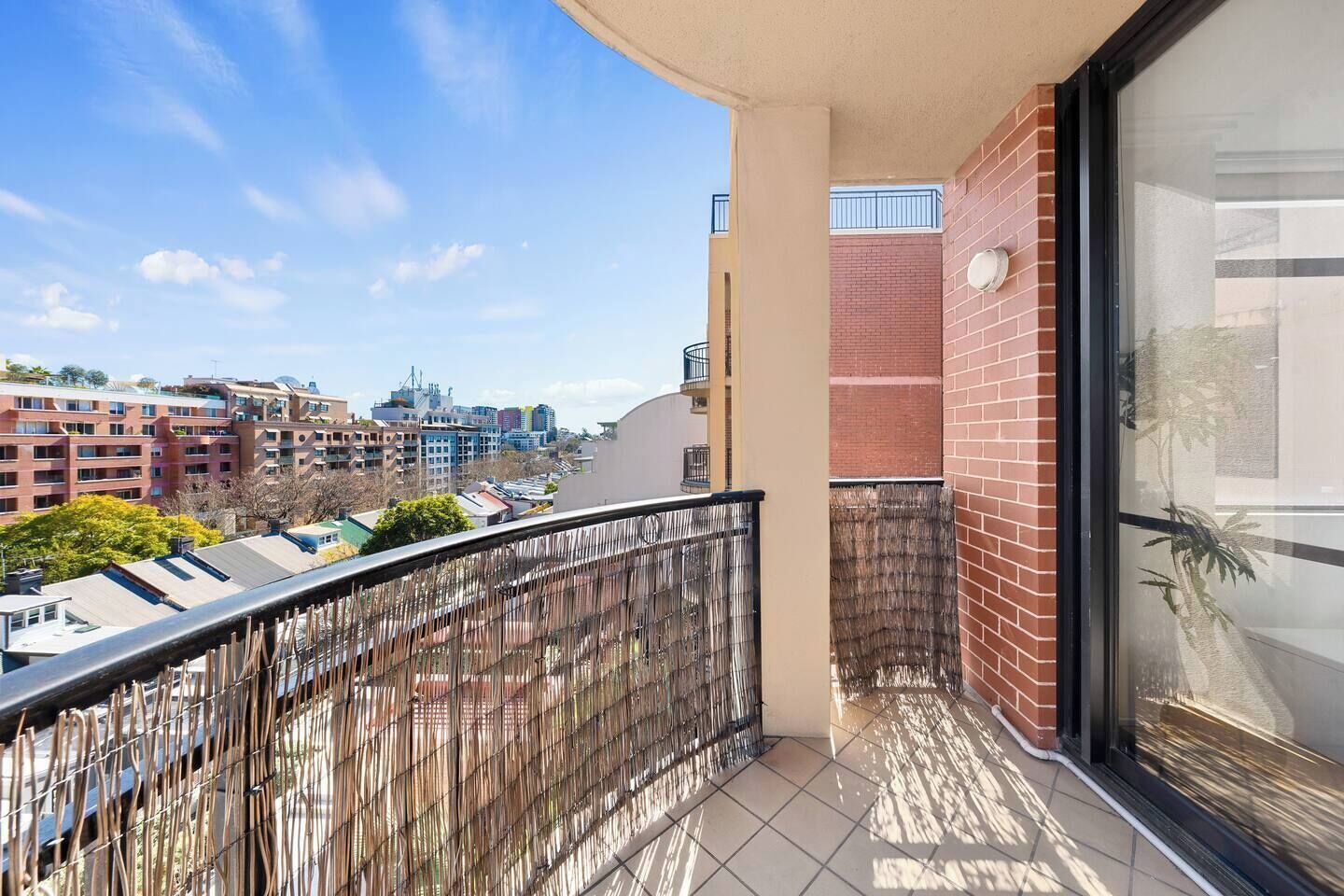 A balcony with a view of a cityscape, including buildings and a clear sky.