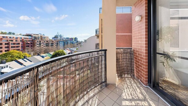 Un balcone con vista su un panorama urbano, che include edifici e un cielo sereno.