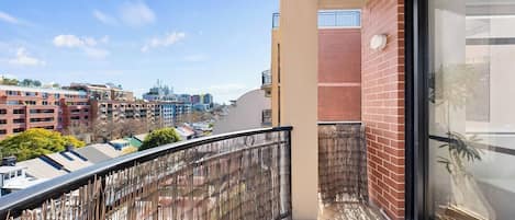 Un balcón con vista a un paisaje urbano, incluyendo edificios y un cielo despejado.