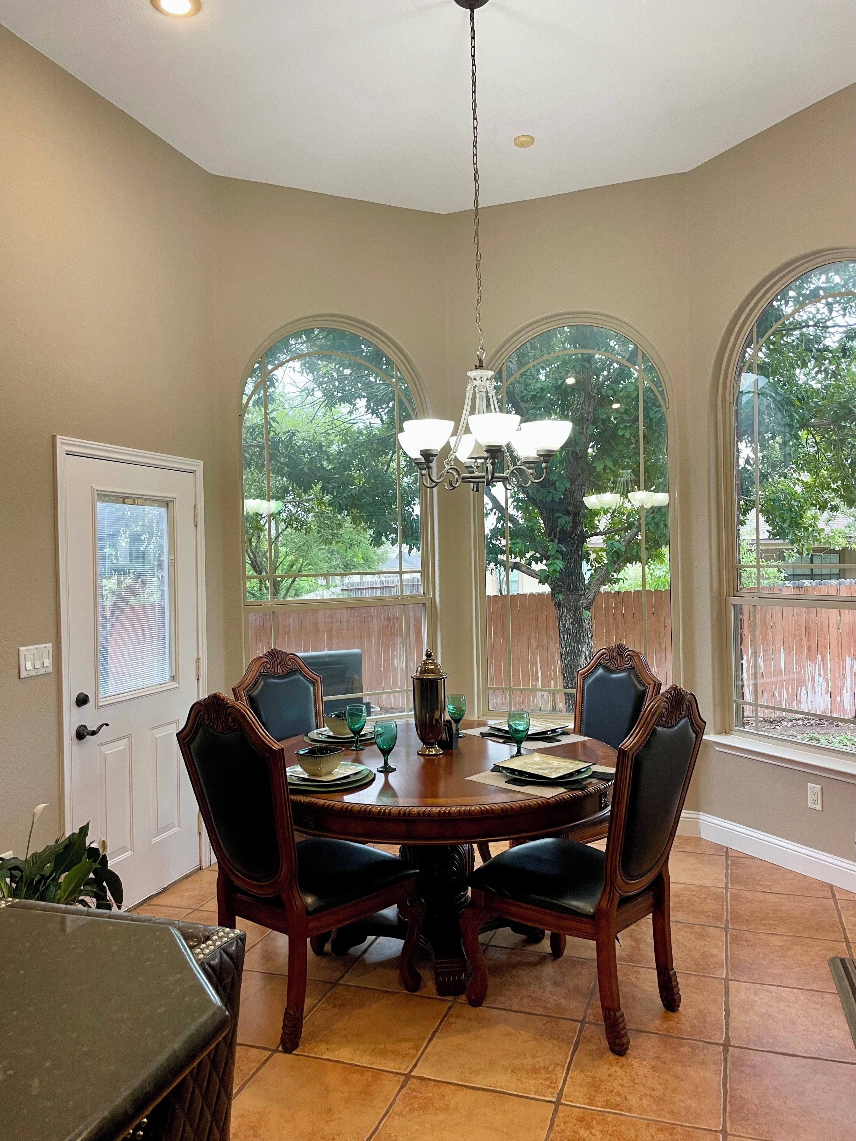 A dining area with a round table, chairs, and a chandelier.