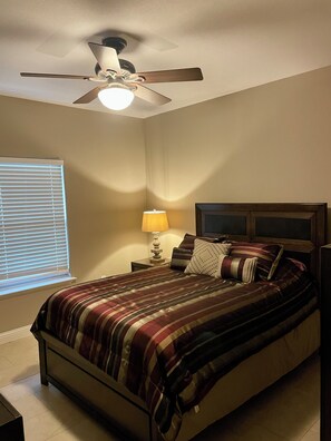 A bedroom with a bed, a nightstand, a lamp, a ceiling fan, and a window with blinds. - Marvelous 3-bedroom house with AC in charming Del Rio (Del Rio)