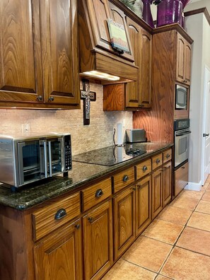 A kitchen with wooden cabinets, a stainless steel microwave, a toaster oven, and a built-in oven. - Marvelous 3-bedroom house with AC in charming Del Rio (Del Rio)