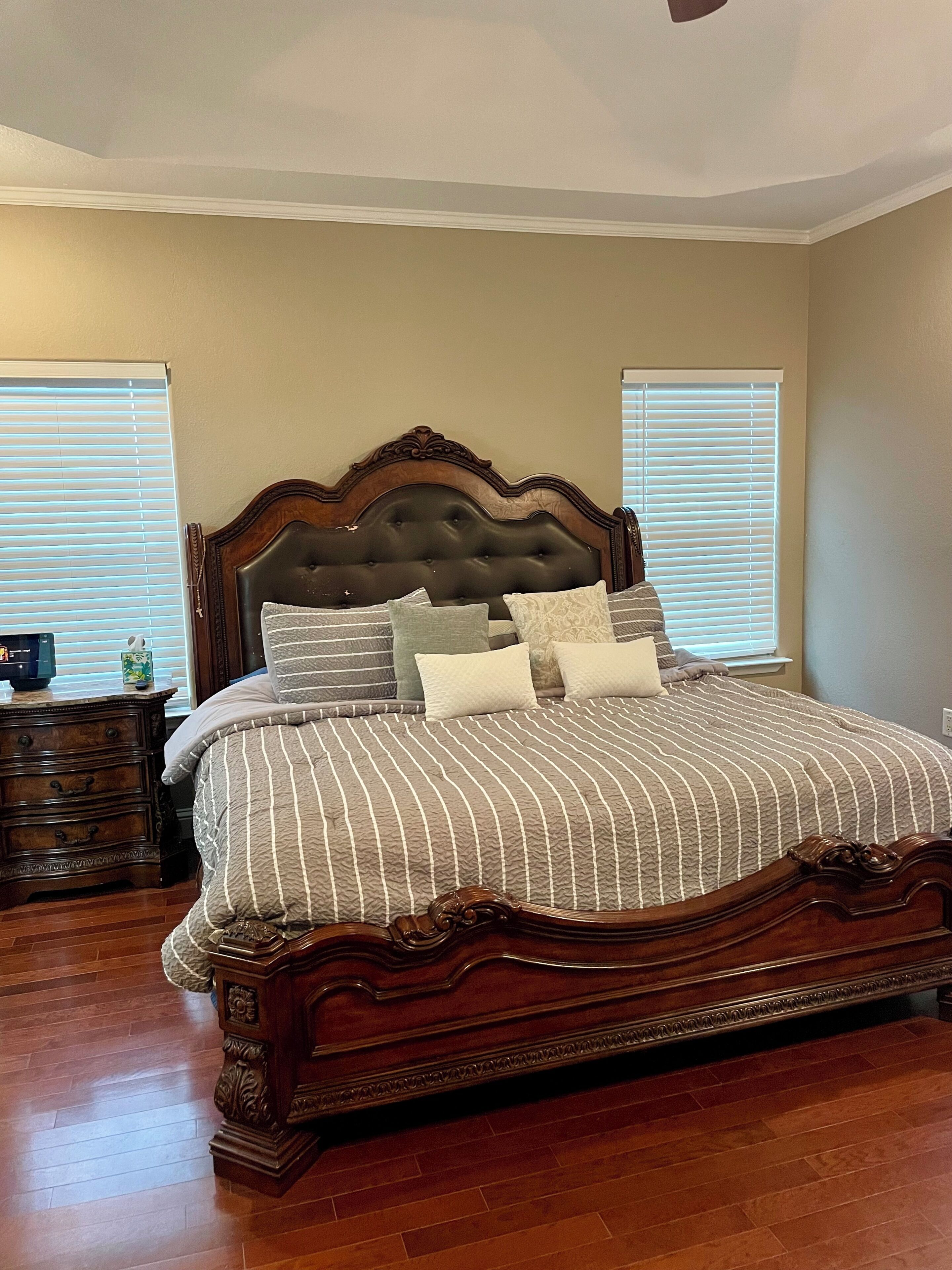 A bedroom with a large bed, wooden headboard, and a nightstand with a lamp.