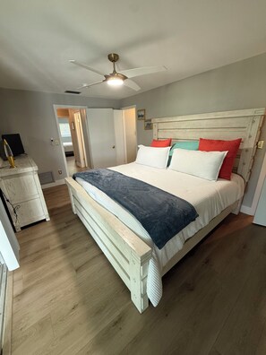 Ein Schlafzimmer mit einem Bett, einem Deckenventilator und einer hölzernen Kommode.