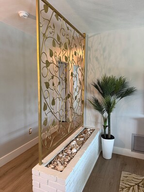A room with a decorative metal partition, a potted plant, and a stone-lined planter. - Retro styled paradise 3bed/2br Cape Coral pool home on the canal front (Cape Coral)