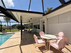 Ein überdachter Patio-Bereich mit Pool, Gartenmöbeln und Blick auf die umliegende Landschaft.