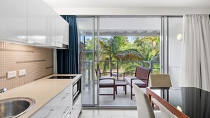 Et moderne køkken med en skydedør til en balkon med havemøbler.