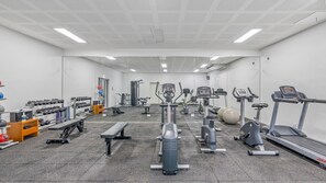 Ein Fitnessstudio mit verschiedenen Trainingsgeräten, darunter Laufbänder, Ergometer und Kurzhanteln.