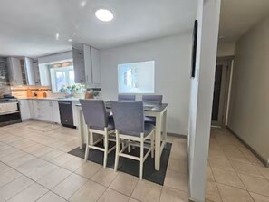 A modern kitchen with a dining area, a large window, and a flat-screen TV. - Near WEM | Entire Home+Full AC+Sleeps8+FreeParking (Edmonton)