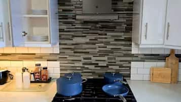 A kitchen with white cabinets, a black stove, and a tiled backsplash.