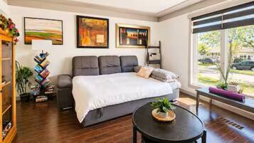 A modern bedroom with a bed, a side table, and a window with a view of the outside.