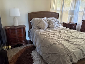 A bedroom with a bed, two nightstands, a lamp on each, and a rug. - Cozy 2-bedroom house in pleasant Green Bay with AC (Green Bay)