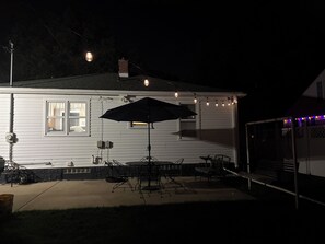 Ein Haus mit einer Terrassenanlage, inklusive Gartenmöbeln und Lichterketten.