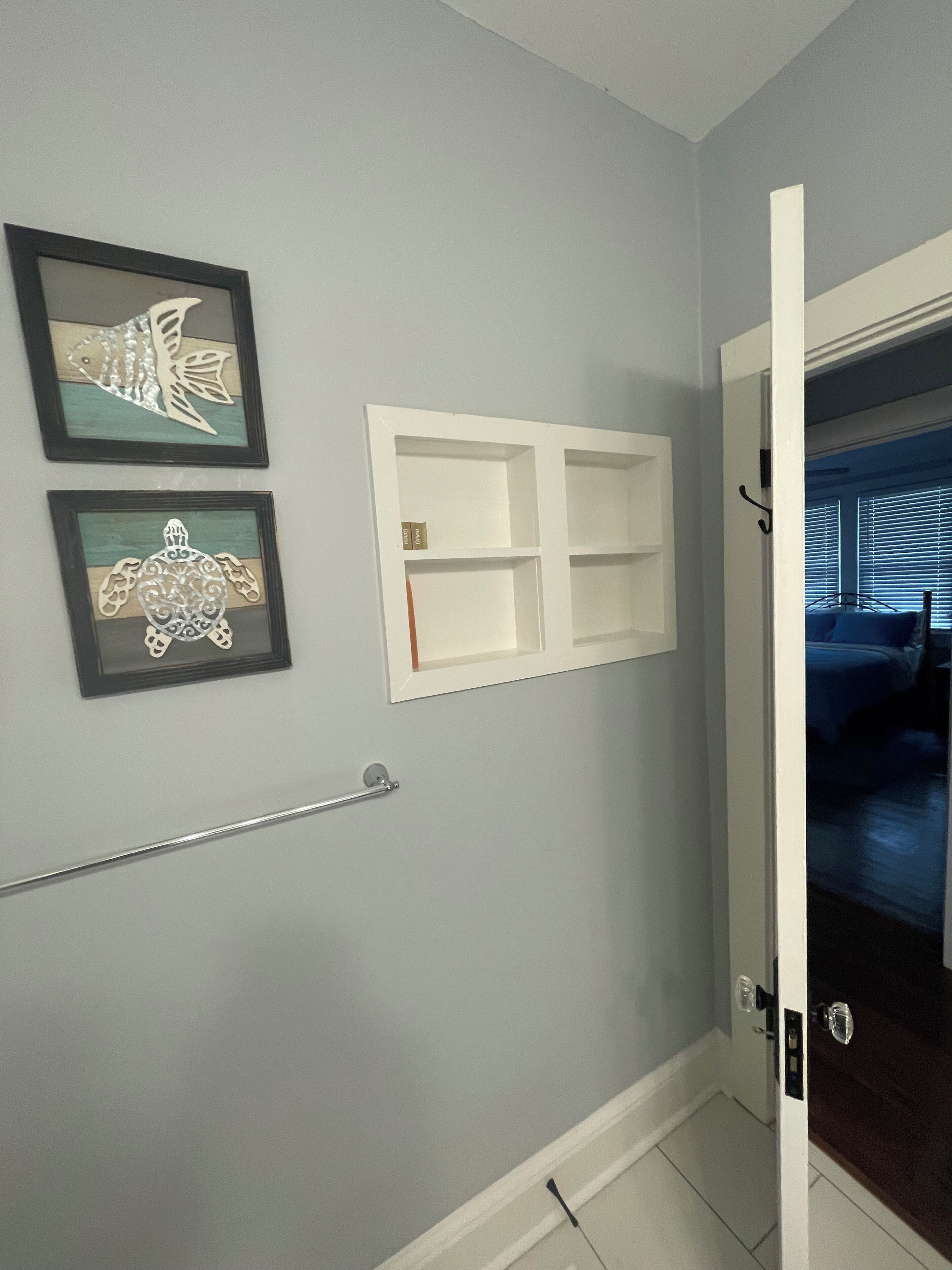 A bathroom with a towel rack, a framed fish and turtle artwork, and a white medicine cabinet.