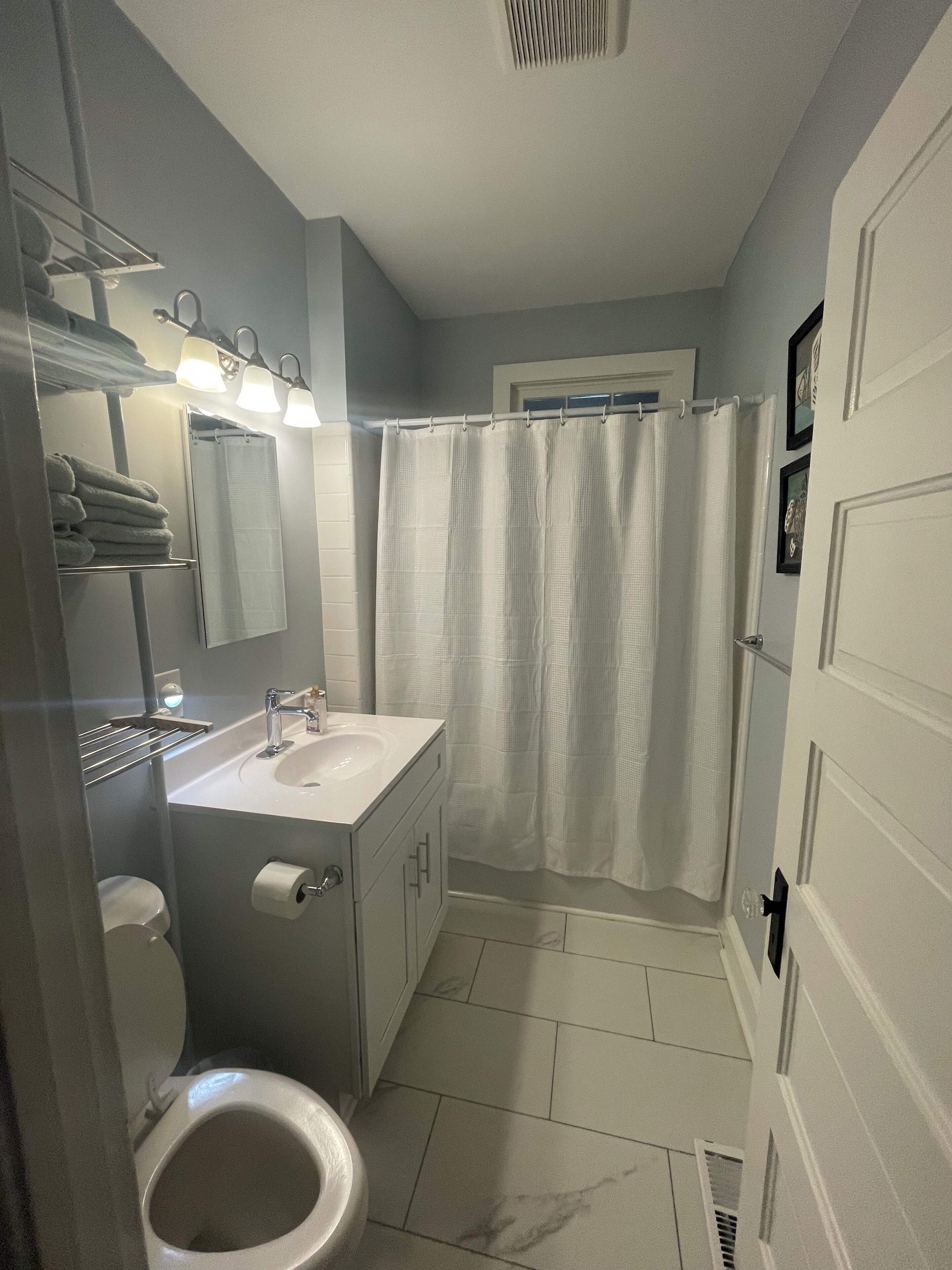 Un baño con inodoro, lavamanos y cortina de ducha.