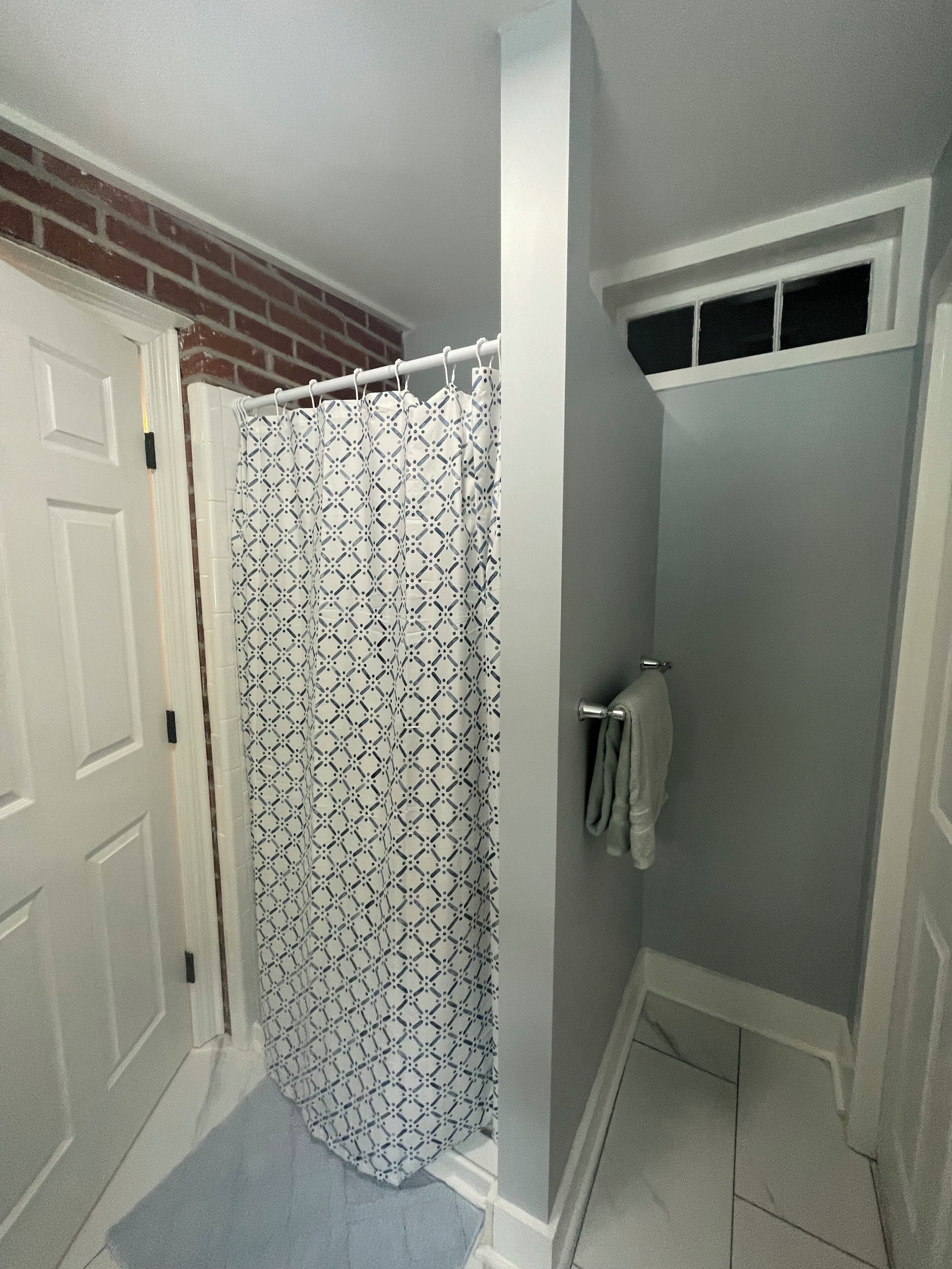Une salle de bain avec un rideau de douche, un porte-serviettes et une porte.