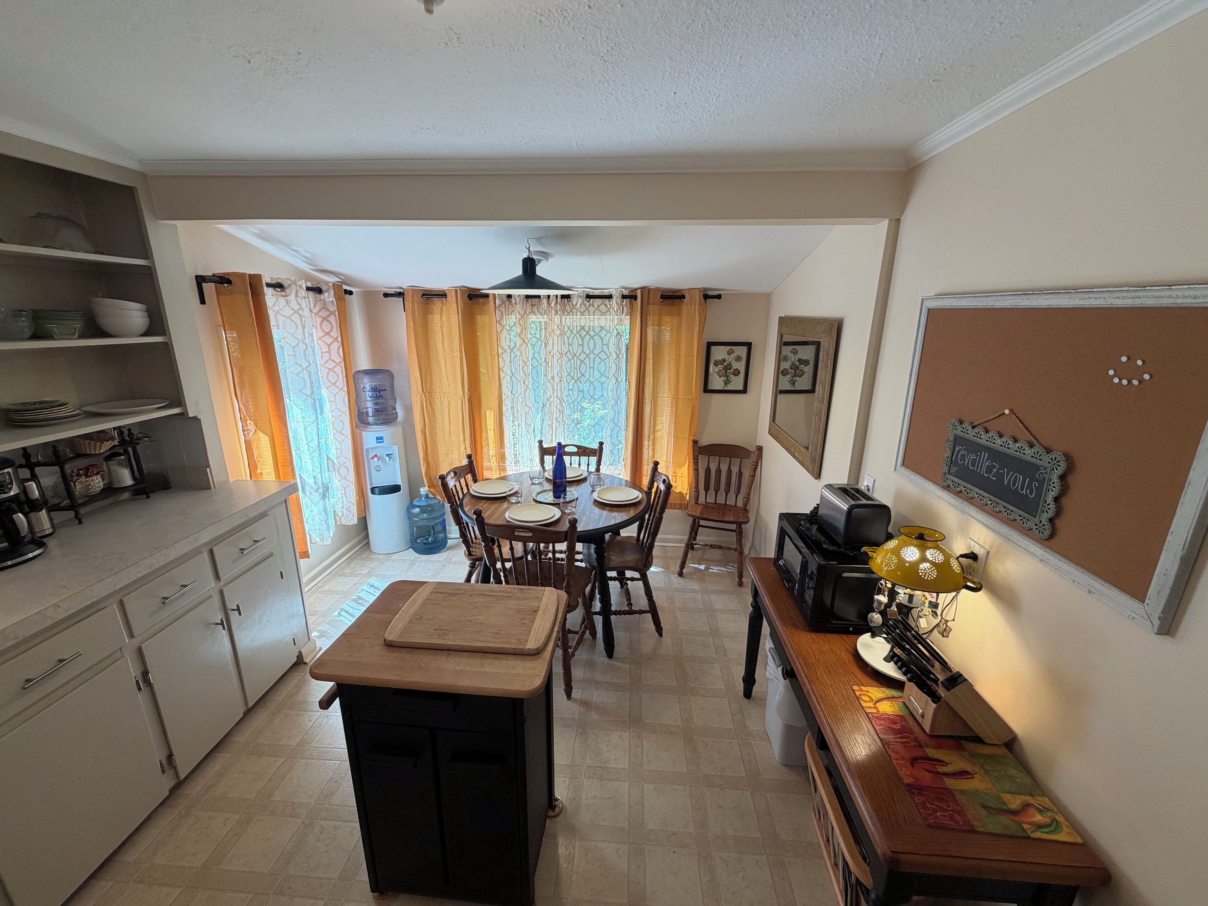 A compact kitchen with a dining area, a water dispenser, and a vintage toaster.