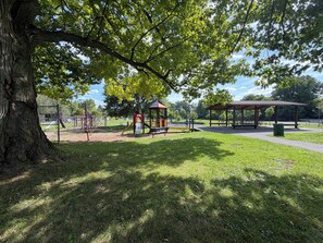 Ein Park mit einem Spielplatz, Picknicktischen und einem überdachten Pavillon.