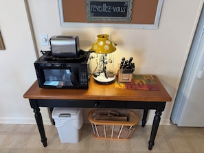 A kitchen counter with a microwave, toaster, yellow lamp, knife block, and a trash bin. - Cozy home minutes from SU campus, area hospitals & all major highways. (Syracuse)