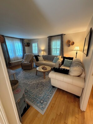 A living room with a sofa, armchairs, a coffee table, and a rug. - Cozy home minutes from SU campus, area hospitals & all major highways. (Syracuse)
