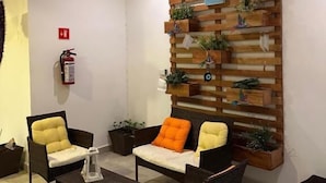 Un vestíbulo con mobiliario de mimbre, una pared vegetal de madera y un extintor.