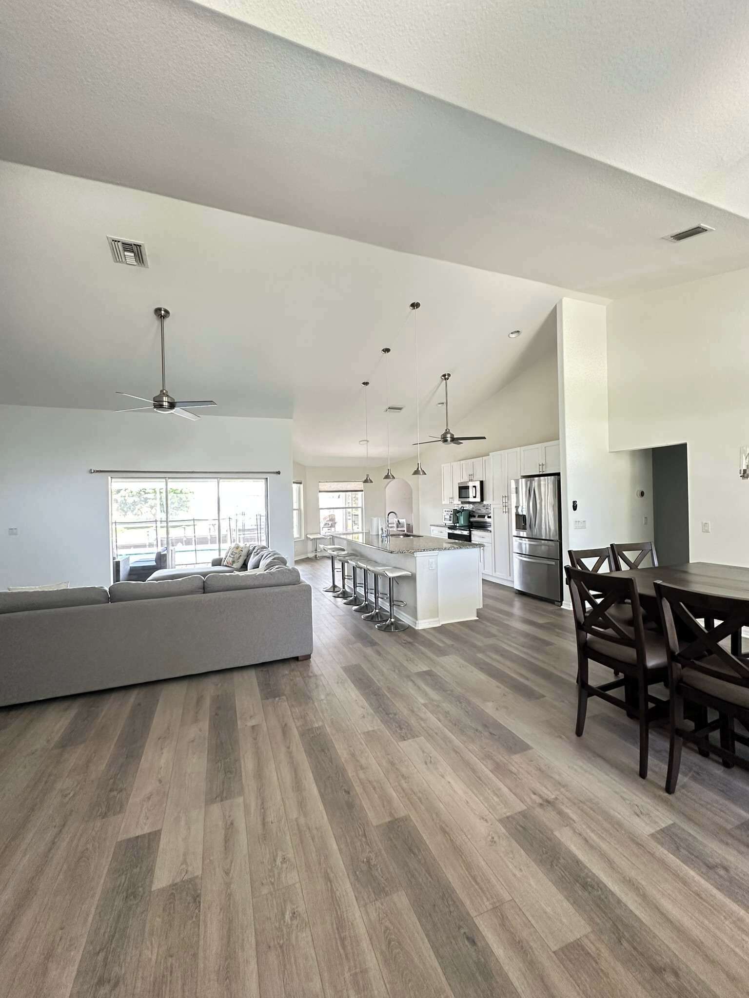 A spacious living area with a large sofa, a dining table with chairs, and a kitchen in the background.