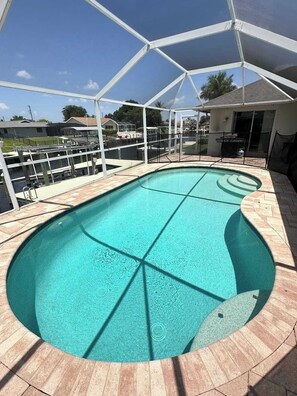 A swimming pool with a clear blue water, surrounded by a covered deck area. - Villa Seashell - Cape Coral (Cape Coral)