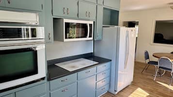 Una cucina con mobili azzurri, un piano di lavoro nero e elettrodomestici in acciaio inossidabile, tra cui un forno a microonde, forno e frigorifero.