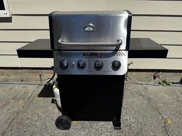 A portable gas grill with a digital display and control knobs, placed on a concrete surface.
