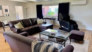 Un salon avec un canapé en cuir, une table basse en verre et un fauteuil de bureau noir.