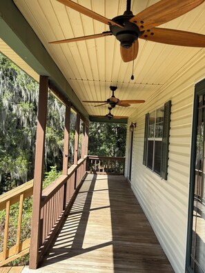 A covered porch with a ceiling fan, wooden railing, and a view of trees and sky. - A Charming 3-bedroom house on Toledo Bend lake with garage and boat house (Many)