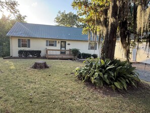 A single-story house with a front porch, a small front yard, and a tree with hanging moss. -  A Charming  3-bedroom house on Toledo Bend lake with garage and boat house (Many)