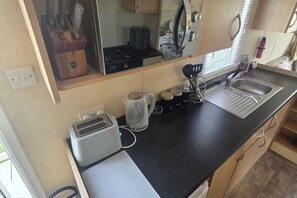 Une petite cuisine équipée d’un grille-pain, d’une bouilloire, d’un évier et de placards.