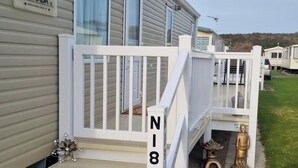 A mobile home with a white deck, a mailbox, and a mailbox number 'N18'.