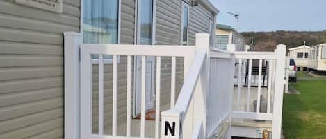 Una casa móvil con un porche blanco, un buzón y el número de buzón 'N18'.