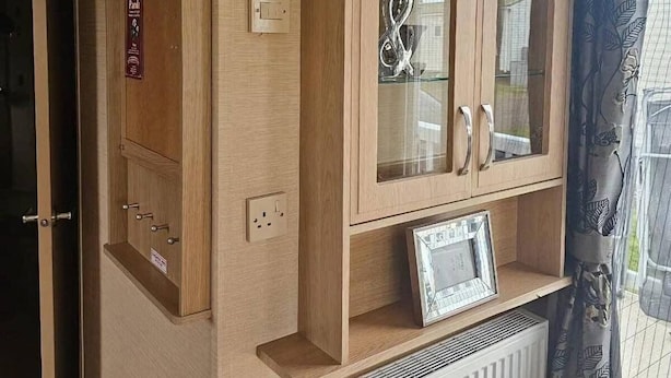 A wooden cabinet with glass doors, a radiator, and a small framed picture.