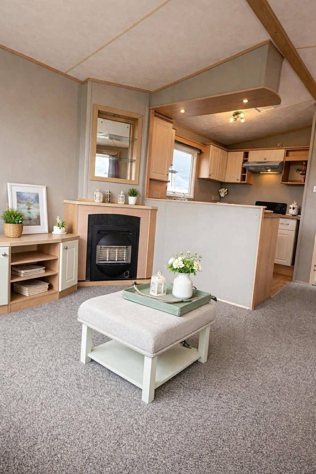 A compact living space with a kitchenette, a fireplace, and a seating area with a tray table.