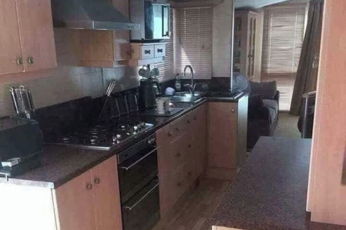 Une cuisine de taille réduite, équipée d’une cuisinière, d’un évier et de placards.