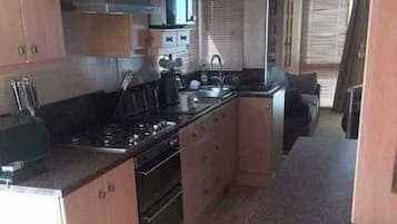 Une cuisine de taille réduite, équipée d’une cuisinière, d’un évier et de placards.