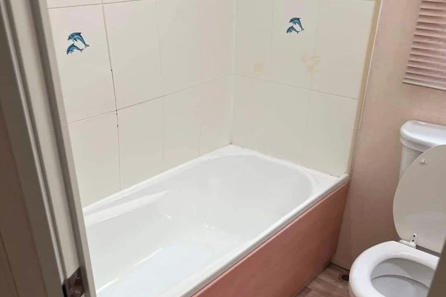Une salle de bain avec une baignoire, des toilettes et des murs carrelés.