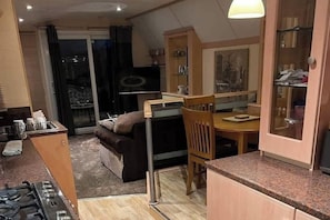 A compact living space with a kitchenette, a dining area, and a sofa. - 2 Bed - Sleeps 6 - Lake View - Beach Access - Pets (Skegness)