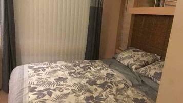 A hotel room with a bed, curtains, and a headboard.