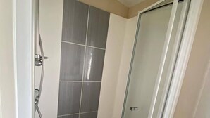 Eine Dusche mit Glastür, Brausekopf und Handbrause.